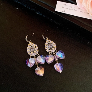 Detailed macro view of vintage gold teardrop earrings with iridescent purple crystals
