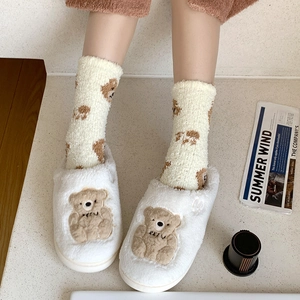 Detail of plush coral fleece slipper socks featuring cute embroidered brown cartoon bear