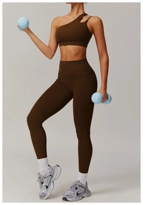Detail of dark brown one-shoulder sports bra and high-waisted leggings with side pockets