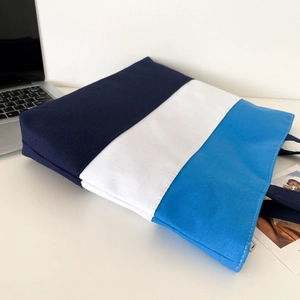 Detail of three-color striped canvas tote bag with zipper and navy handles