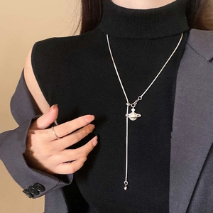 Détail du collier pendentif Saturne en zircon avec pompon perle sur tricot noir chic