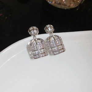 Detailed macro view of silver cage earrings with pearls and zircon stones on white porcelain