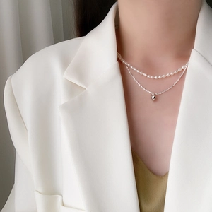 Double-layer necklace featuring fresh water pearls and silver heart pendant on a model