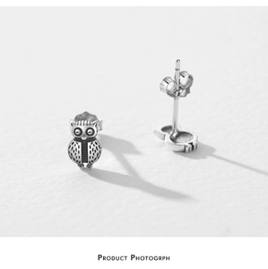 Macro detail of S925 sterling silver owl stud earrings showing metal texture and backings