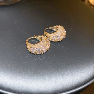 Macro shot of gold-plated hoop earrings with micro-pave cubic zirconia on black leather