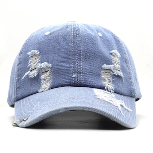 Vue de face d'une casquette en jean bleu clair avec anneaux métalliques et détails usés