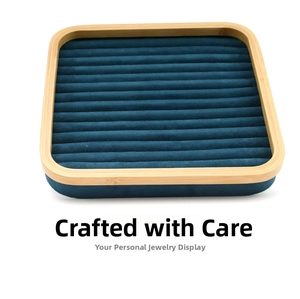 Detailed top view of a bamboo jewelry tray with dark teal velvet slots for rings