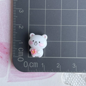 Miniature white resin bear figurine holding a pink flower shown with measurement scale