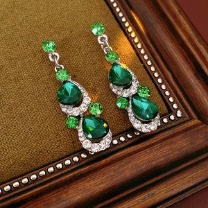 Detail of vintage teardrop earrings with green rhinestones and a gold metal finish