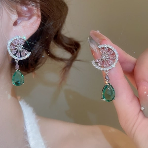 Detail of silver drop earrings with emerald green and pink stones in moon setting