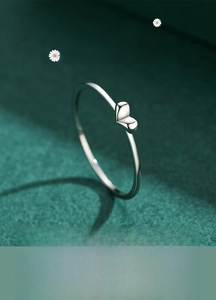 Close-up of minimalist s925 silver heart ring on a dark green textured surface