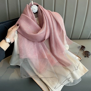 Close-up of pink gradient silk scarf with shimmering gold thread and smooth texture