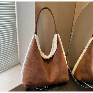 Detail of contrast brown suede tote bag with white plush trim on a desk with soft shadows