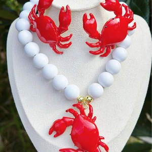 Set gioielli estivi con ciondolo a granchio rosso, collana di perline bianche e orecchini.