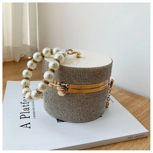 Detailed view of silver cylindrical evening bag with rhinestones and pearl handle