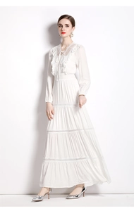 Detail von weißem Maxikleid mit aufwendiger Spitzenhäkelarbeit und gestuftem Rockteil