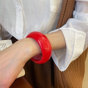 Detail of a bright red wide resin bangle with a smooth glossy finish for women