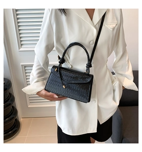 Detail of black pleated texture shoulder bag styled with a professional white suit jacket