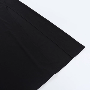 Detail view of the side slit and double-stitched hem on the black knitted midi dress
