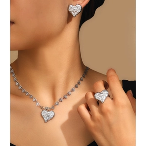 Detailed view of silver heart jewelry set with unique textured hammered finish on a model
