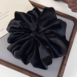 Detail shot of a large black velvet scrunchie showing premium texture and soft fabric folds