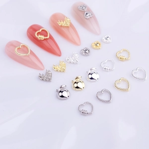 Macro detail of mini 3D heart-shaped metal nail charms in silver and gold plating
