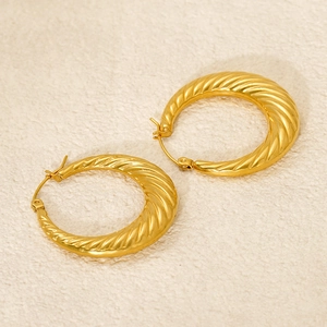 Detailed macro view of gold-plated hoop earrings with unique spiral texture and sleek finish