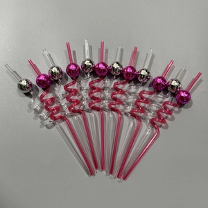 Close-up of pink and silver disco ball mirror ornaments on spiral plastic straws for parties