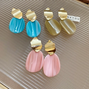 Detail of irregular oval earrings in blue, amber, and pink marble resin with gold metal