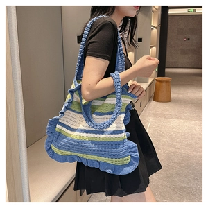 Detail of hand-knitted tote bag featuring blue green white stripes and ruffle edges