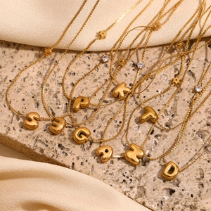Vue macro de pendentifs lettres bulles en or avec zircons sur un fond en soie élégant