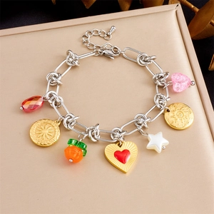 Detailed shot of charms bracelet with heart, bow, and flower charms on a beige box