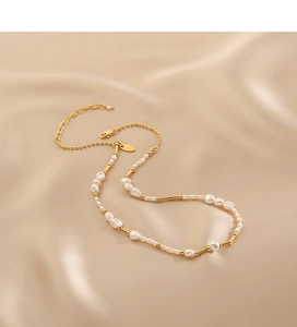 Detailed macro view of baroque pearls and gold metal beads on champagne satin background