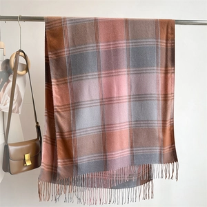 Detail of warm pink and brown plaid cashmere-like scarf with thick fringe edges
