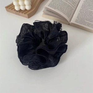 Vue détaillée d'un chouchou en dentelle noire avec froufrous sur un livre avec bougie
