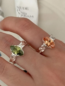 Macro detail of 925 silver rings with marquise-cut olive green and amber orange zircons