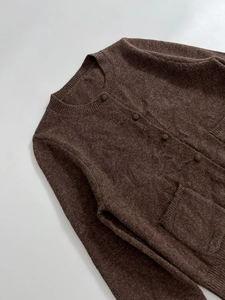 Close-up of deep brown knit cardigan with ribbed cuffs and matching buttons detail