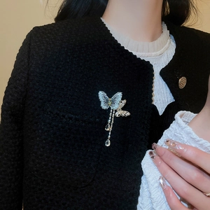 Close-up of luxury butterfly tassel brooch with blue zircon on black tweed jacket