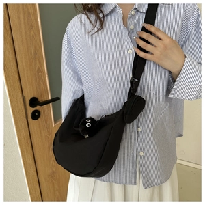 Detail of black tote bag with wide strap and plush soot sprite charm accessory