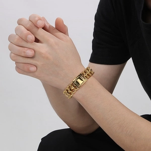 Gros plan d'un bracelet chaîne à maillons dorés avec fermoir rectangulaire porté au poignet