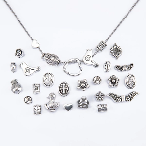 Silver alloy jewelry making kit with delicate necklace chain and various charms on white background