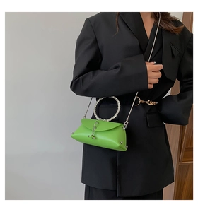 Detail showing bright green leather crossbody bag with rhinestone handle and chain strap