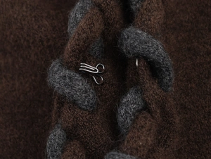 Gros plan du cardigan en maille marron avec texture tressée et crochet en métal argenté