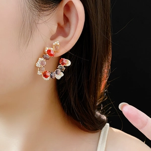 Macro shot of U-shaped gold earrings with colorful gemstones and small rhinestones