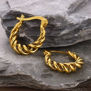 Macro shot of 18k gold plated twisted hoop earrings on natural stone texture
