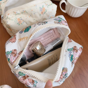 Detail of soft quilted makeup bag featuring bear prints and floral patterns on wood desk
