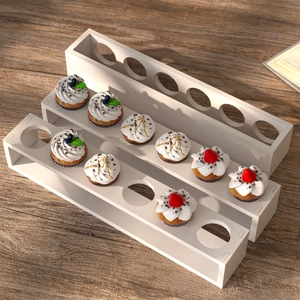 White tiered cupcake display stand with circular slots on a minimalist wooden table