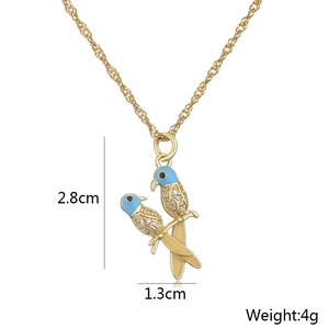 Close-up of 18K gold parrot pendant necklace with blue enamel and zircon details