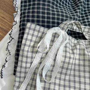 Detail view of black and white plaid fabric with delicate white lace trim on the tote bag