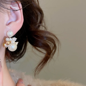 Gros plan de boucles d'oreilles dorées 14 carats avec perles et zircons sur l'oreille